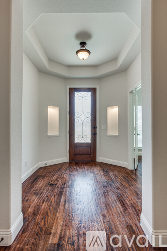A hallway with wood floors and a light brown door.