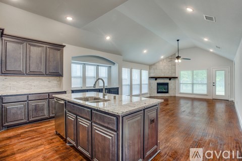 A kitchen with dark wood cabinets and a marble countertop.