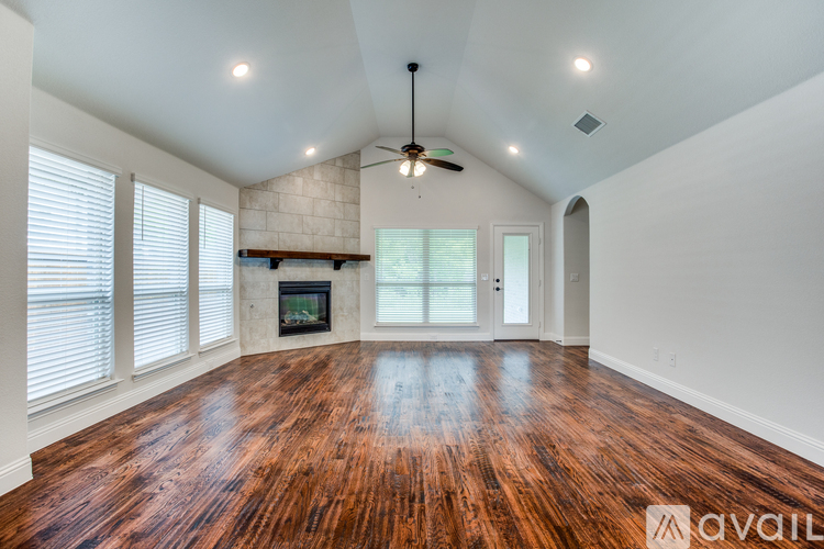 A spacious room with wooden flooring and a fireplace.
