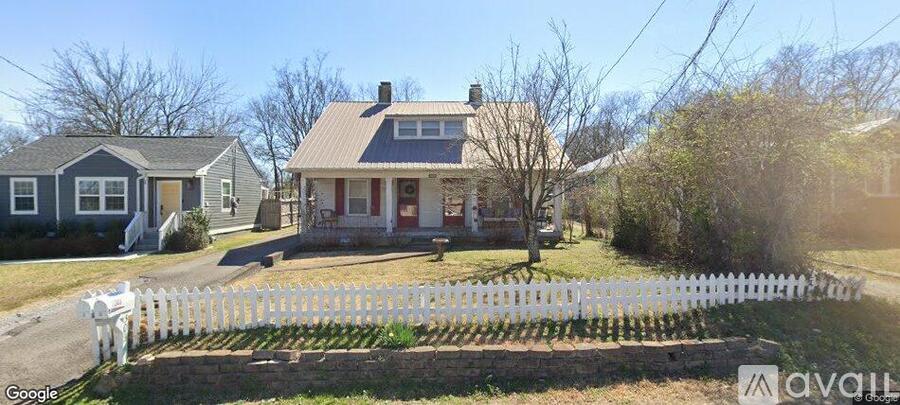 A white picket fence surrounds a house with a red door.