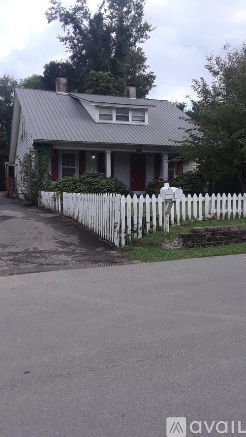 A house with a grey roof and a white picket fence.