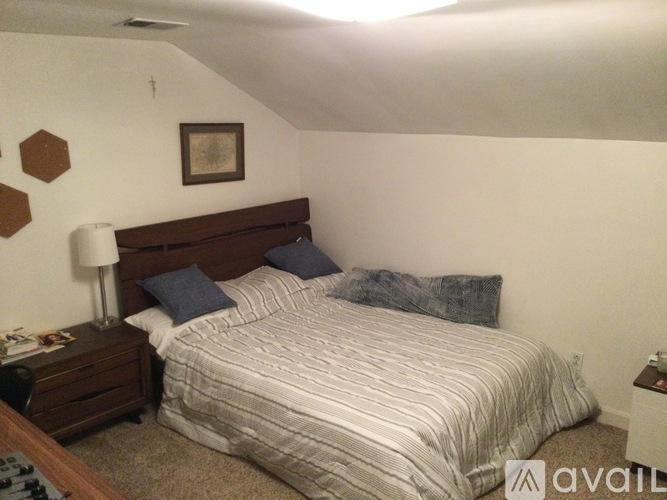 A bedroom with a bed, nightstand, and lamp.