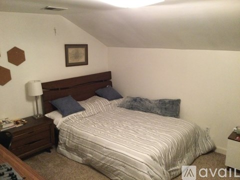 A bedroom with a bed, nightstand, and lamp.