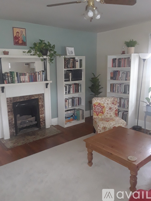 A living room with a fireplace, bookshelves, and a chair.