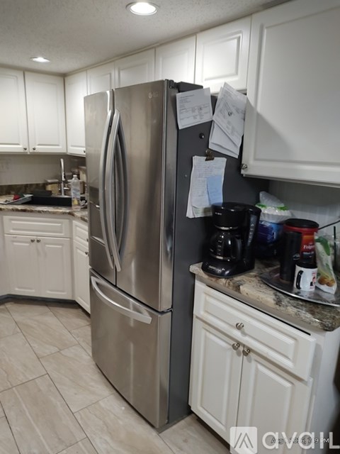 A kitchen with a stainless steel refrigerator and white cabinets.