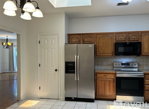A kitchen with a stainless steel refrigerator and wooden cabinets.