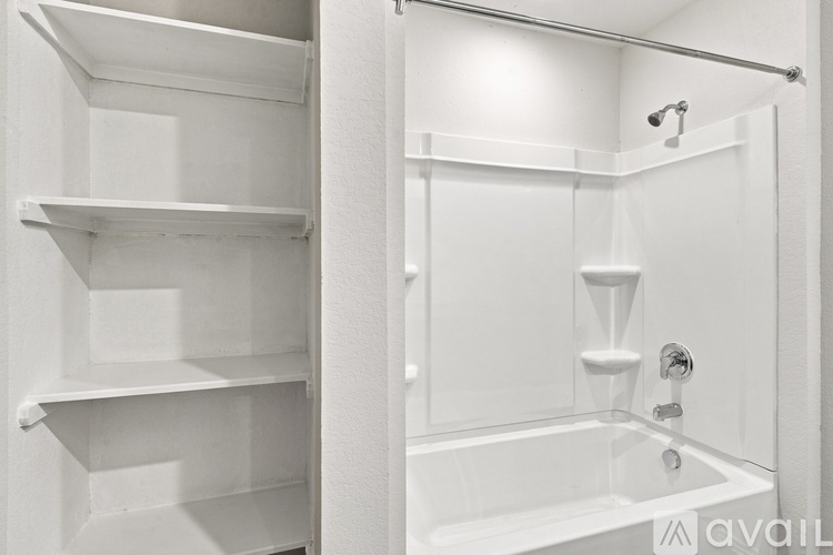 A white bathroom with a tub and shelves.