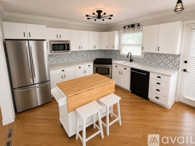 A kitchen with white cabinets and a wooden island.