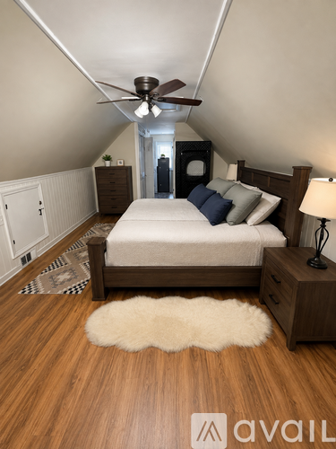 A bedroom with a bed, nightstand, and a rug on the floor.