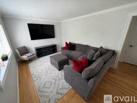 A living room with a grey couch and a flat screen TV mounted on the wall.