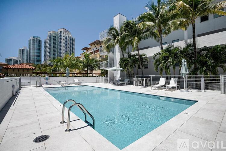 A pool surrounded by palm trees and buildings.
