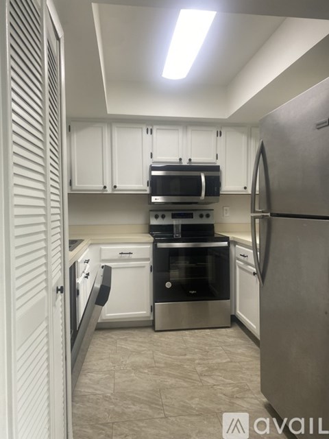 A kitchen with white cabinets and a stainless steel refrigerator.