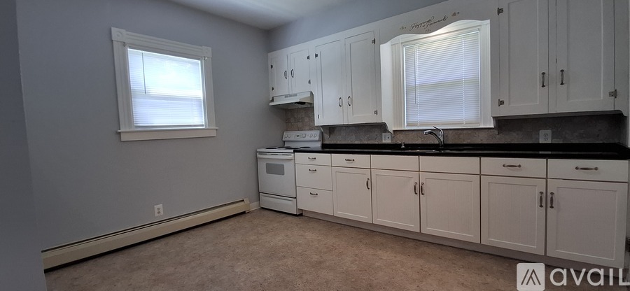 A kitchen with white cabinets and black countertops is available.