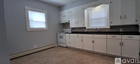 A kitchen with white cabinets and black countertops is available.