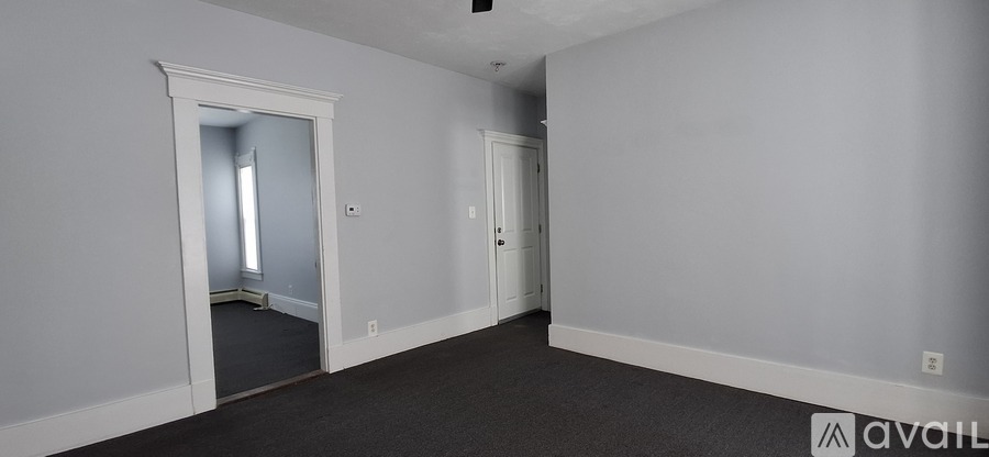 A room with a carpeted floor and a doorway leading to another room.