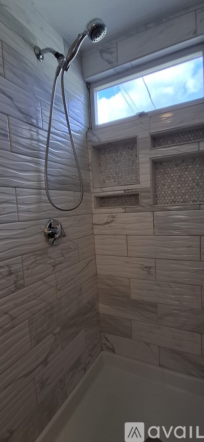 A bathroom with a shower head and a window.