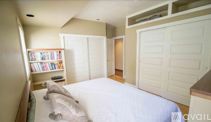A bedroom with a large bed and a bookshelf filled with books.