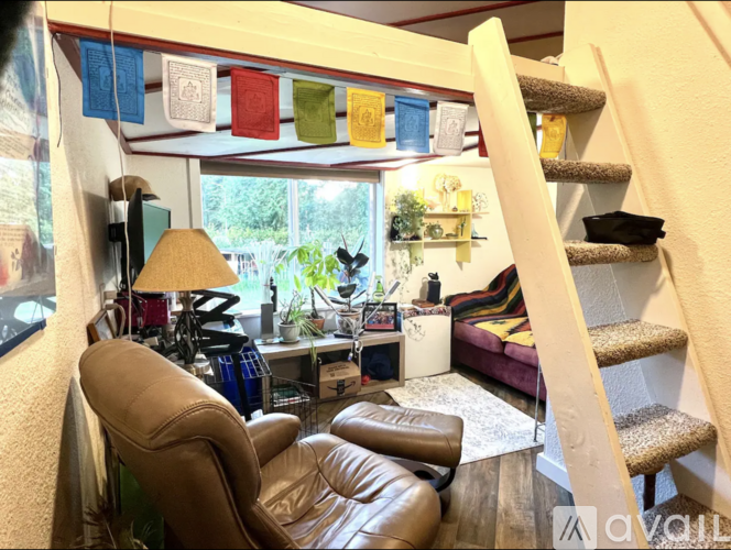 A living room with a brown leather chair and a staircase.