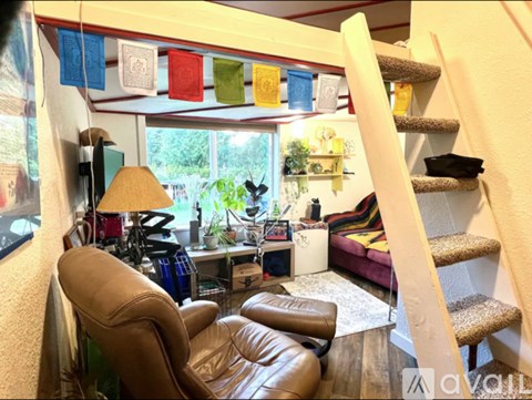 A living room with a brown leather chair and a staircase.