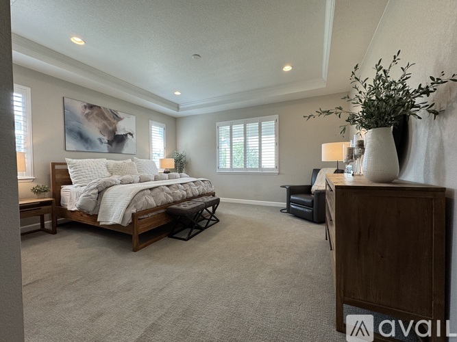 A bedroom with a large bed and a painting on the wall.