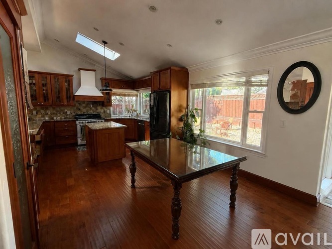 A kitchen with wooden floors and a table in the middle.