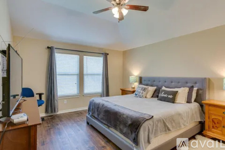 A bedroom with a bed, a dresser, and a ceiling fan.