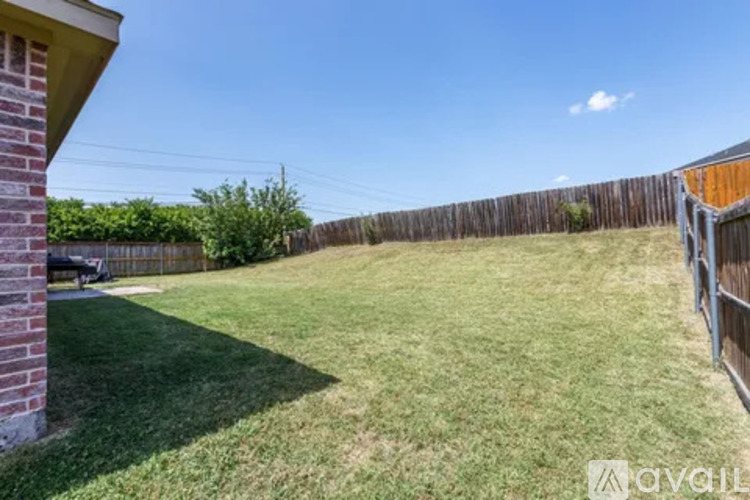 A backyard with a wooden fence and a grassy area.