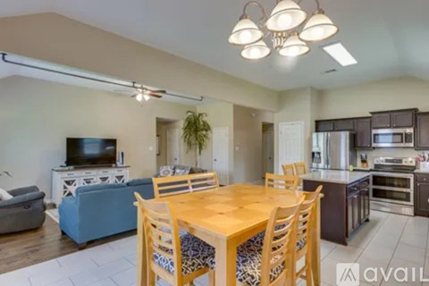 A kitchen with a dining table and chairs in the foreground and a television on a stand in the living room.