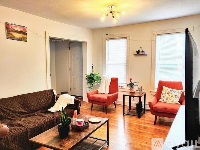 A living room with a brown couch, red chairs, and a wooden coffee table.