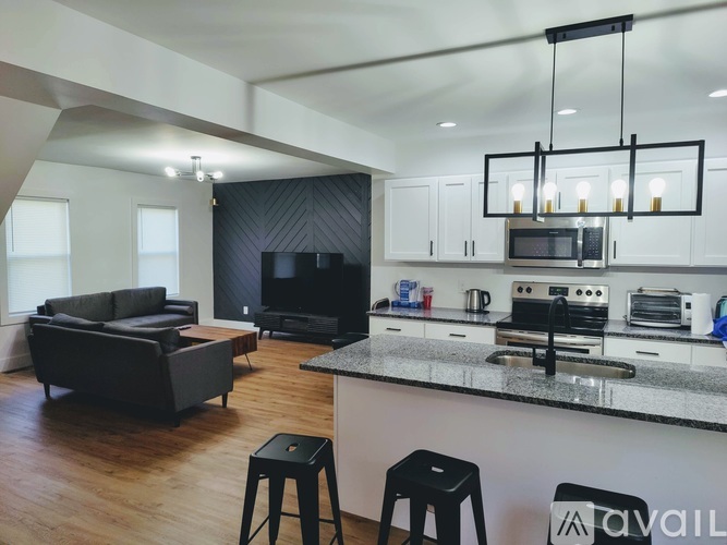 A modern kitchen with a black countertop and stools.