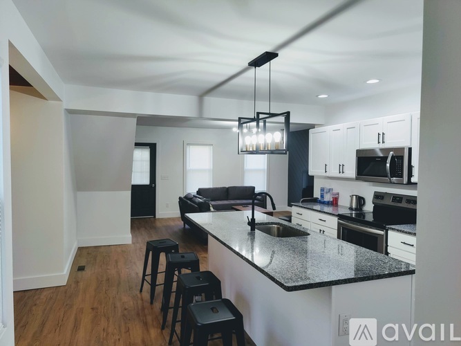 A kitchen with a black countertop and a bar stool.