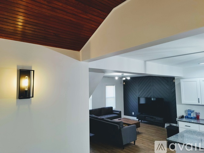 A modern living room with a black couch and a wooden ceiling.