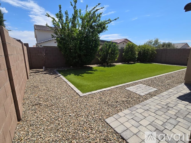 A backyard with a gravel area and a small grassy area.