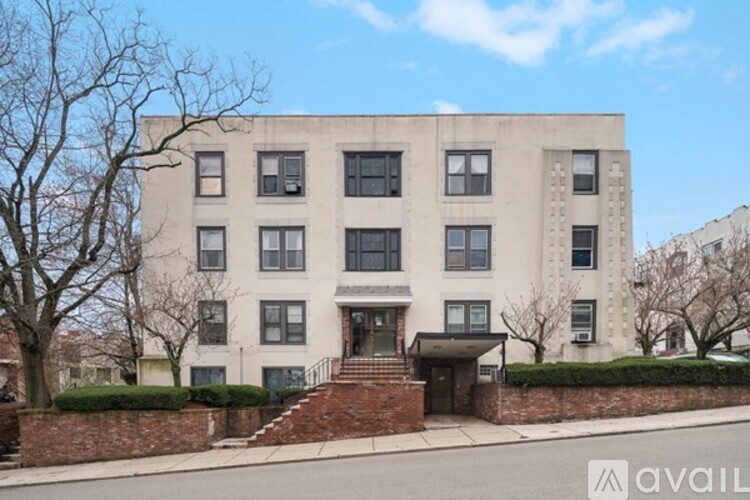A large, beige building with a brick staircase leading to the front door.