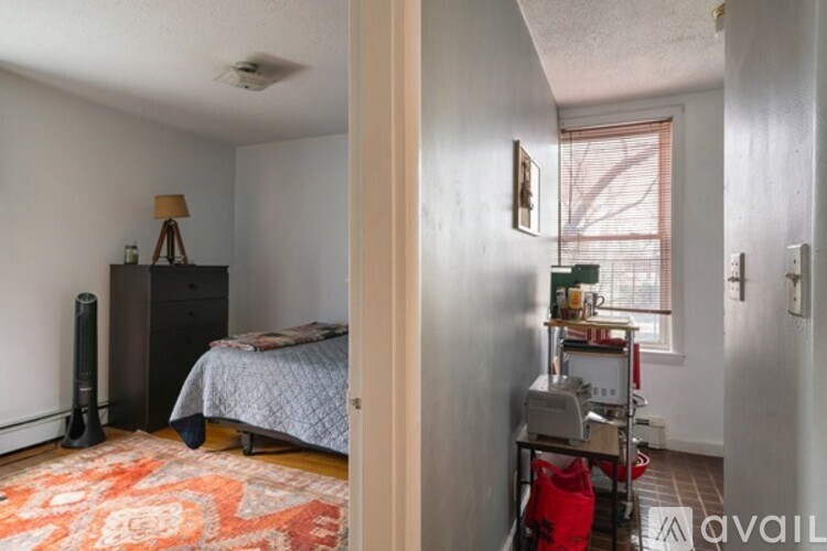 A bedroom with a bed, a chair, and a table with a lamp on it.