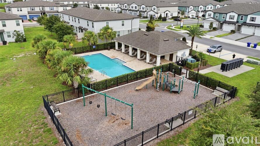 A playground with a slide and swings is surrounded by a black fence.