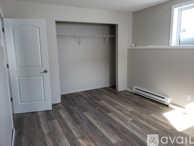 A room with a white door and a grey wall with a wooden floor.