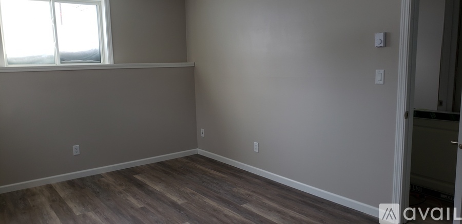 A room with a window and wooden flooring.