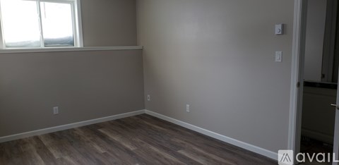 A room with a window and wooden flooring.
