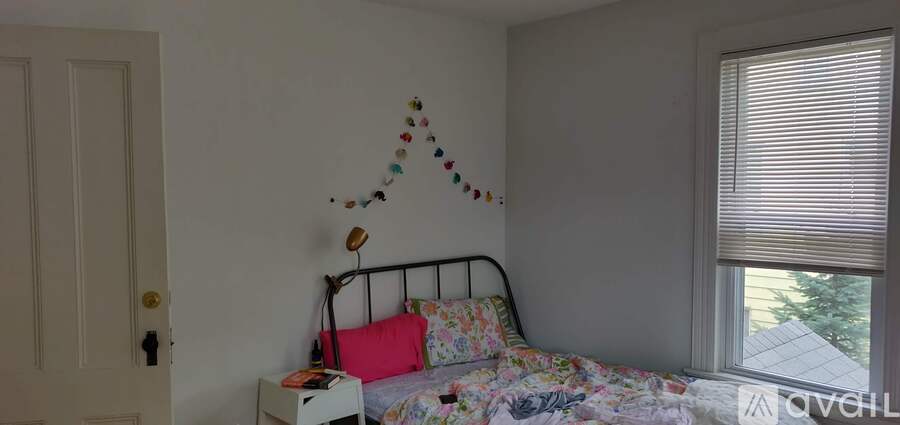 A bedroom with a bed, pillow, and a window with blinds.