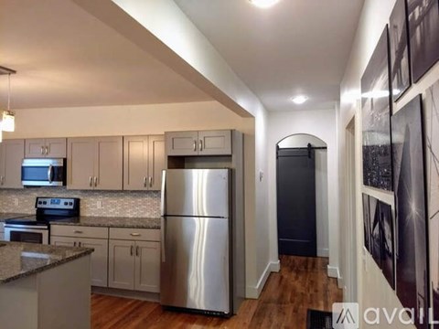 A kitchen with a stainless steel refrigerator and wooden floors.