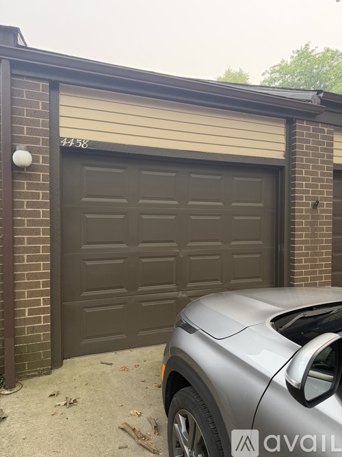 A silver car is parked in front of a brown garage door.