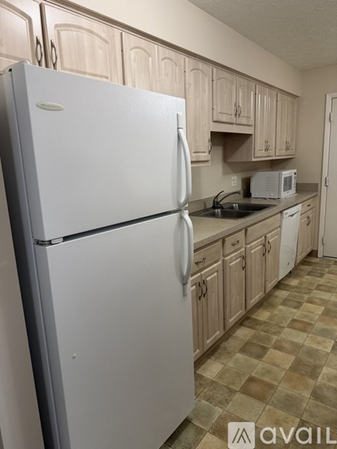 A white refrigerator in a kitchen with wooden cabinets.