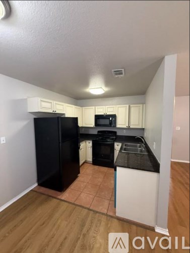 A kitchen with black appliances and white cabinets.