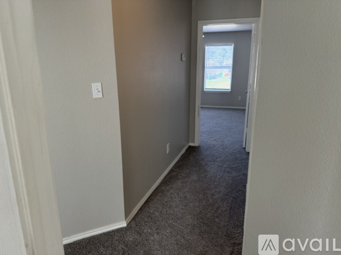 A hallway with a carpeted floor and a doorway leading to another room.