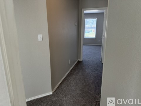 A hallway with a carpeted floor and a doorway leading to another room.