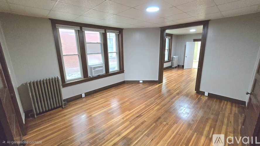 A room with wooden floors and a window with a view of a red building outside.