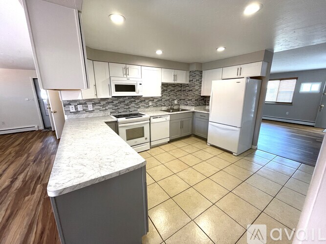 A kitchen with white cabinets and a stone backsplash.