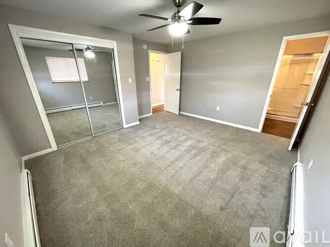 A spacious room with a ceiling fan and carpeted floor.