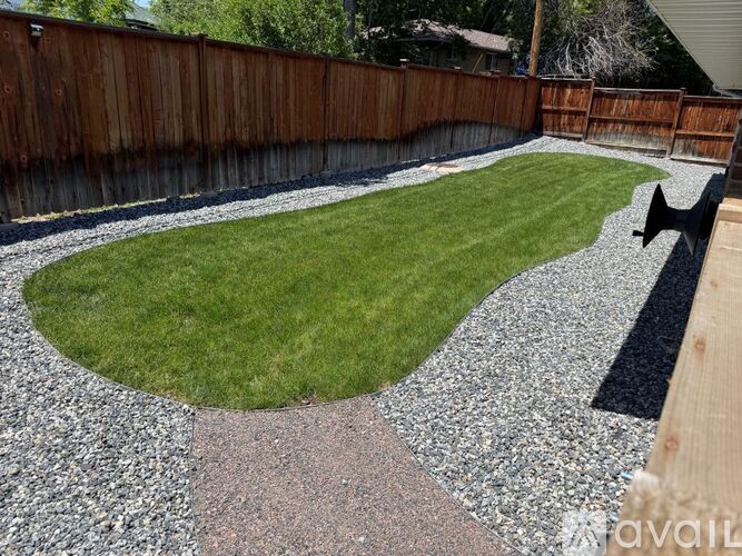 A backyard with a gravel path and a grassy area.